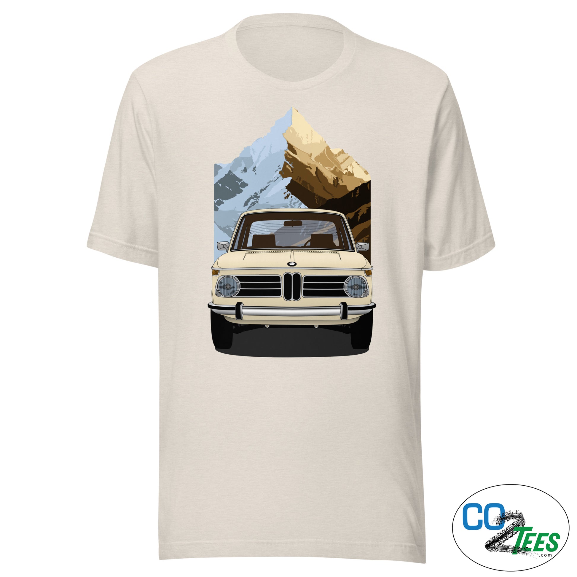 Beige t-shirt with a graphic of a vintage car and mountain landscape on a white background
